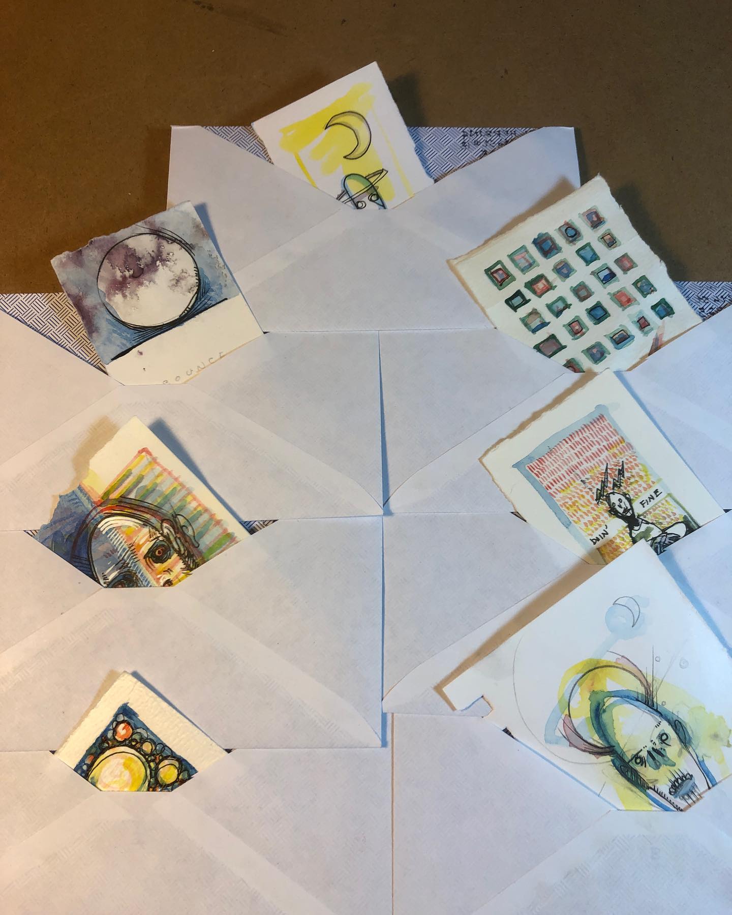 Seven small ink/watercolor drawings arranged at 45 degree angles within white mailing envelopes